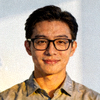足彩策略专家陈先生的肖像照片，年轻男性戴黑框眼镜